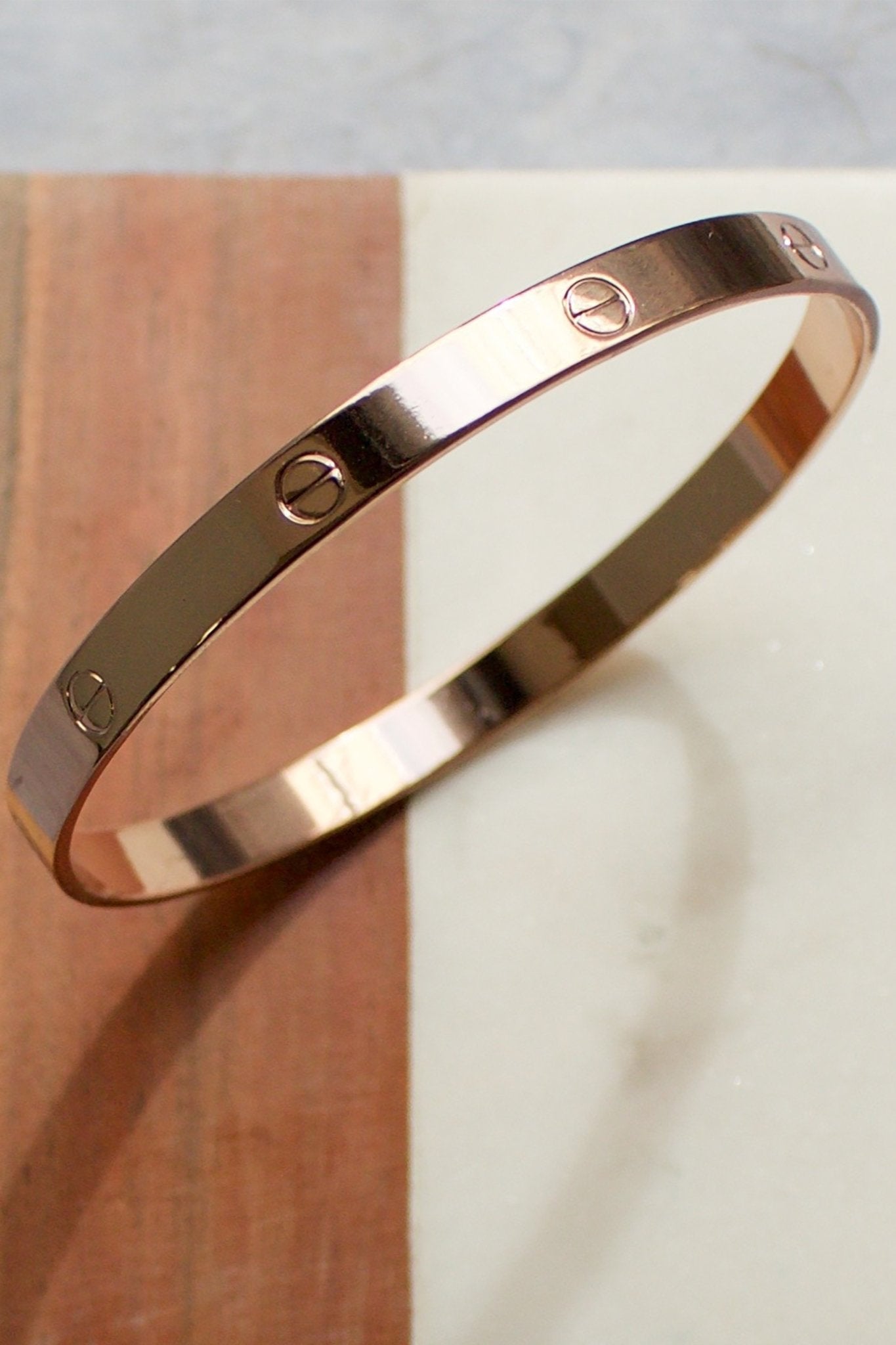 NYC Nailhead Rose Gold Bangle on a wooden table - L'Atelier Global
