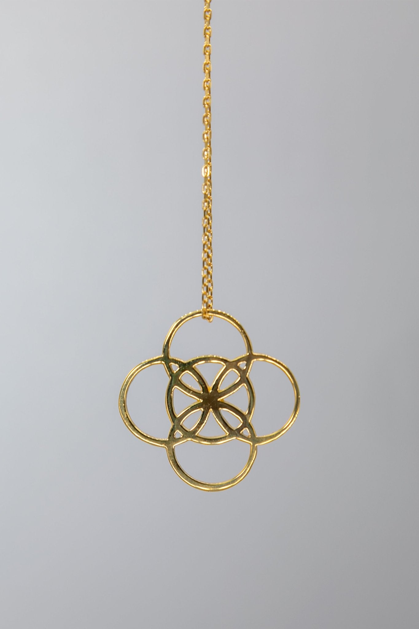 Irish Serenity Gold Necklace hanging on a gray background - L'Atelier Global