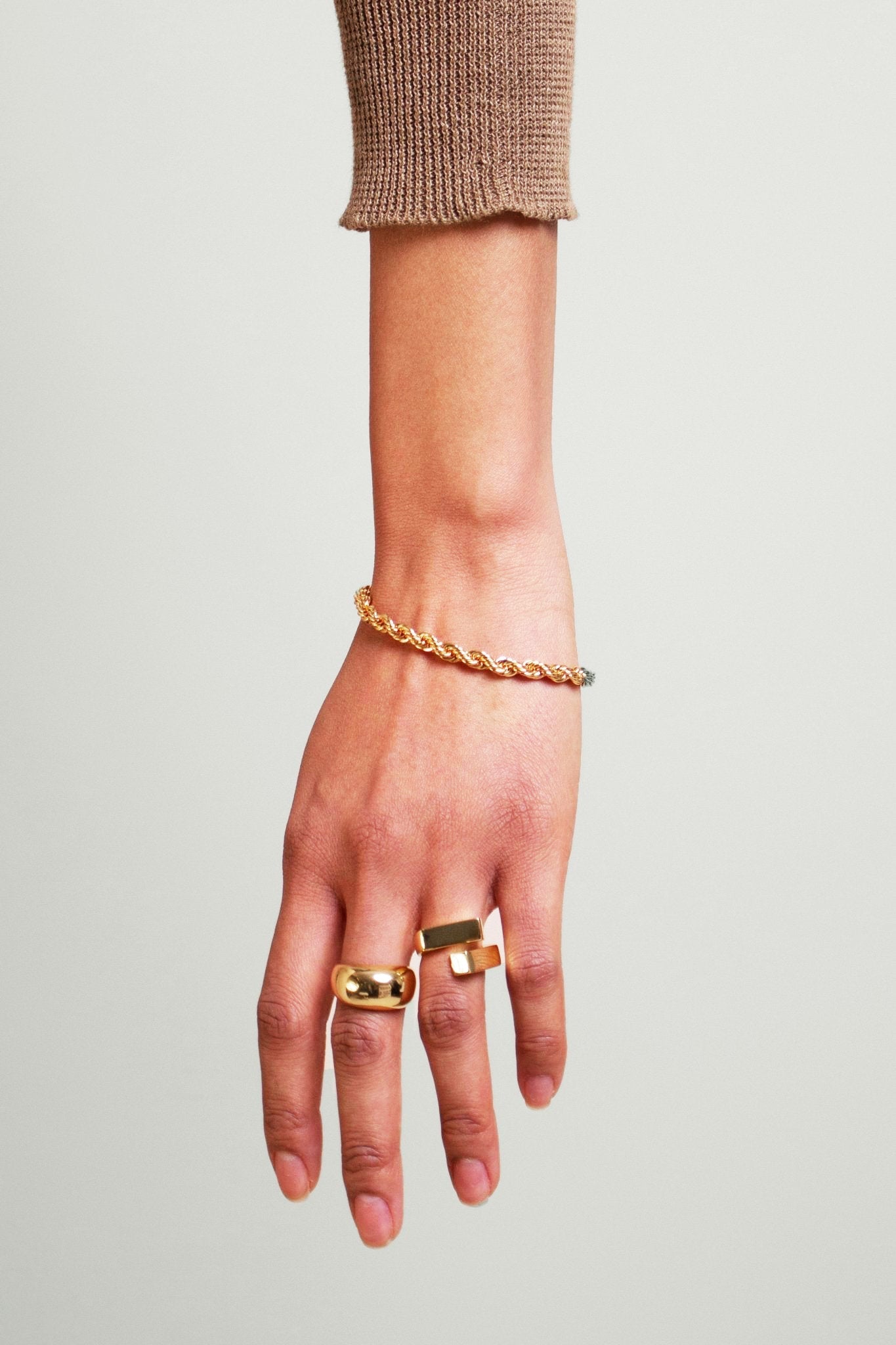 Textured 18K Yellow Gold Rope Chain Bracelet on a model's wrist touching her white skirt - L'Atelier Global