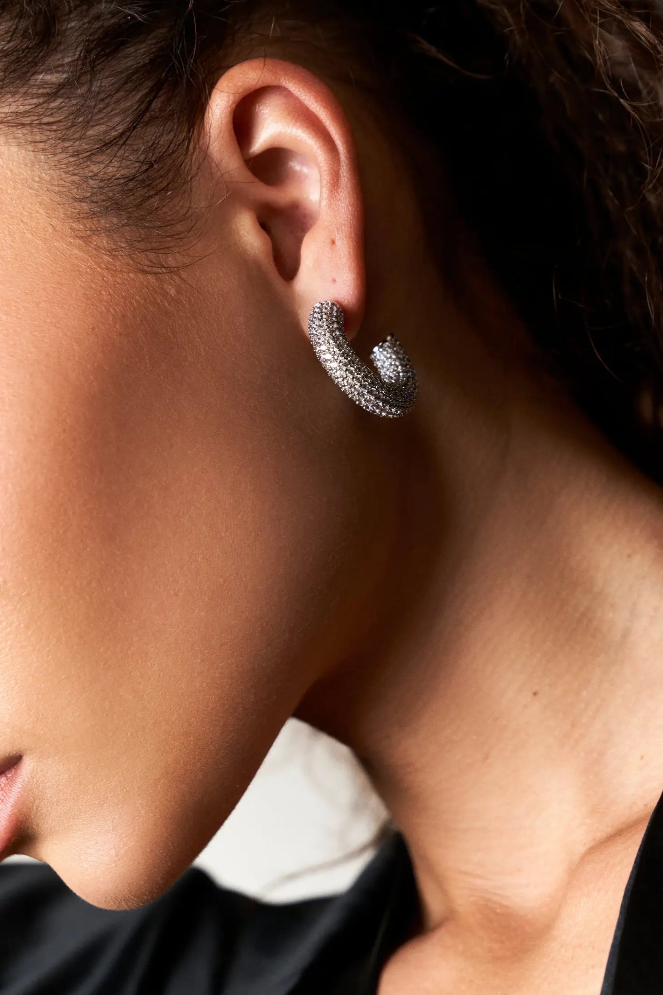 A female model is wearing the Uptown Minimalist Pave Hoops. Image showing her left profile - L'Atelier Global