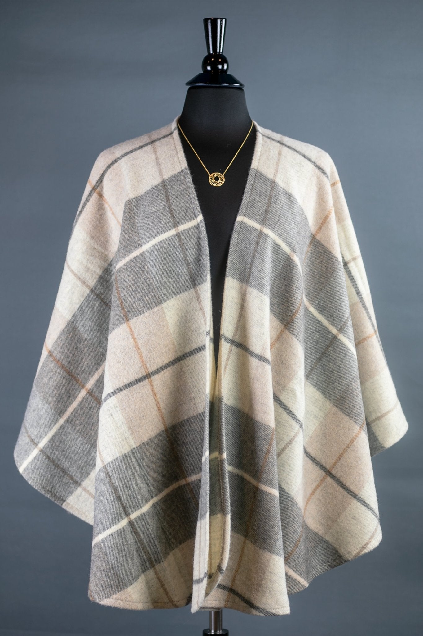 Winter Cozy Tartan Ruana Wrap on a black bust form in front of a gray background - L'Atelier Global